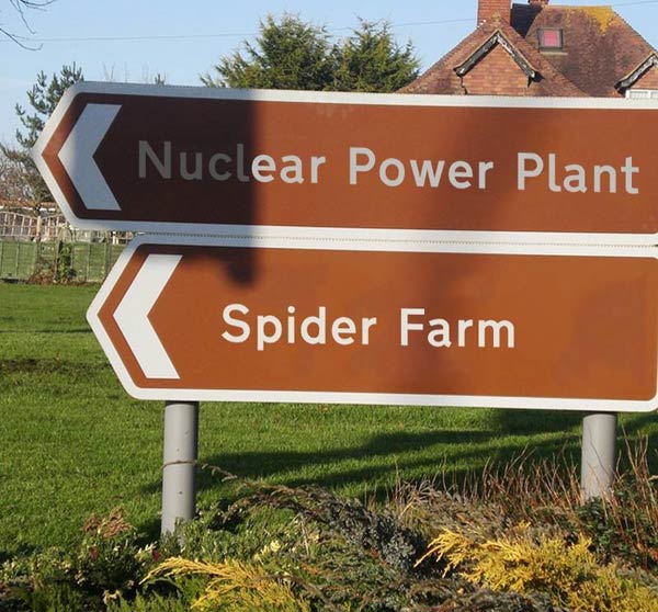 two signs pointing left say nuclear plant and spider farm.