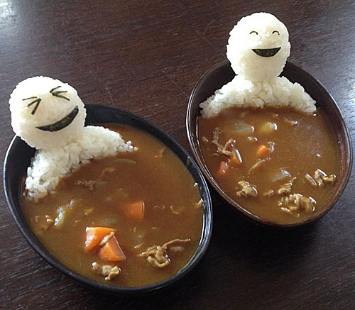 Two small bowls of beef noodle soup. Each contain a laughing person sitting there smiling as if they were in a hot tub.