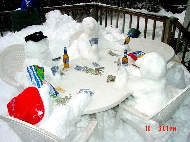 Snowmen playing cards with beer bottles and snacks at a frozen outside table