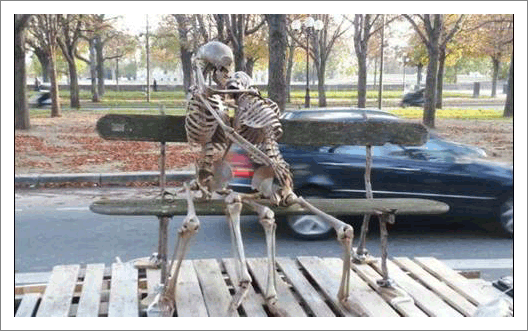 Two skeletons on a park bench kissing passionately. 